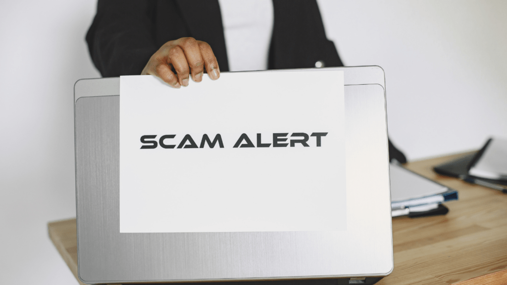 A businessperson holding a scam alert sign