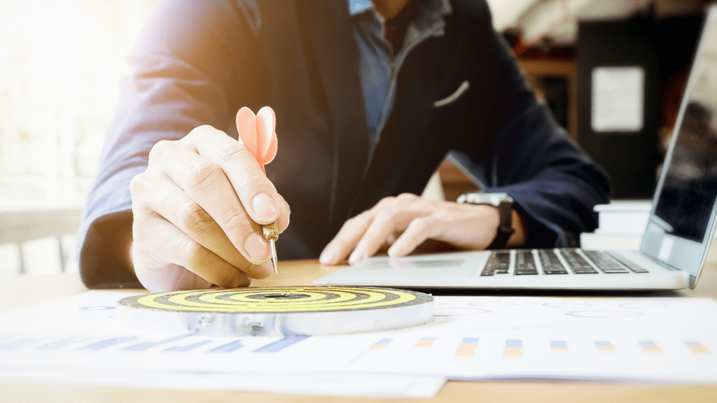 A hand drawing a target on a business plan on a laptop