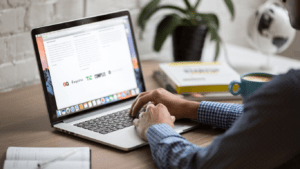 a person sitting at a desk with a laptop and a cup of coffee