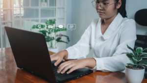 a person in a white shirt is typing on a laptop