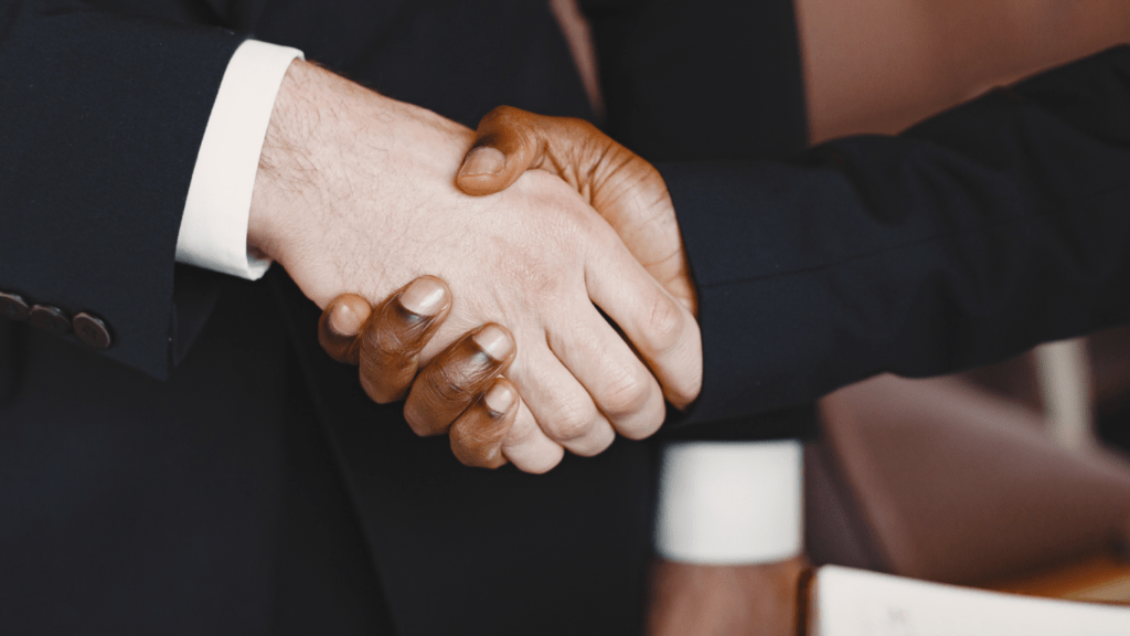 Two business people shaking hands in front of each other