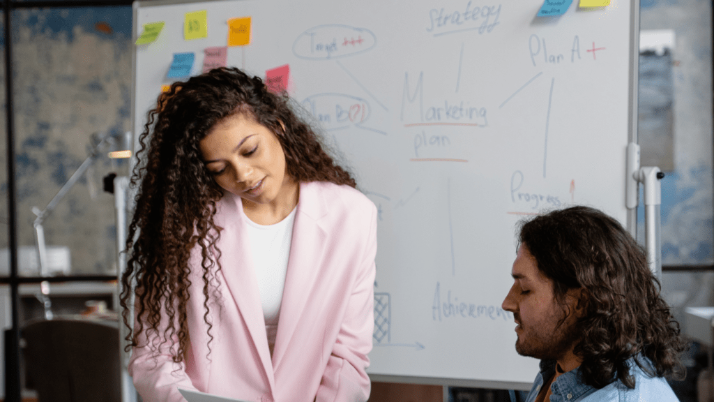 a group of people sitting around a table with a whiteboard