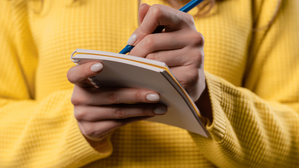 a person is holding a pen and writing in a notebook