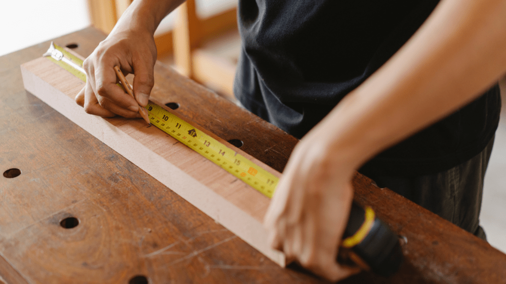 a person is using a ruler to measure a piece of wood