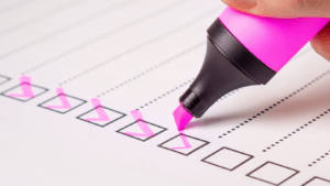 a pink pen is used to mark a checklist on a piece of paper