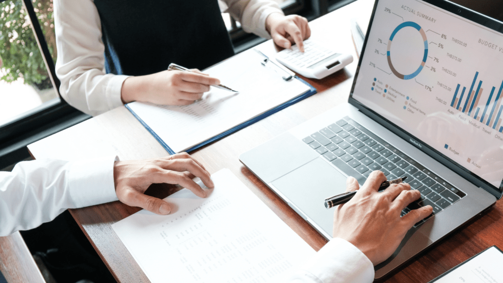 a group of business people sitting around a table with graphs and papers