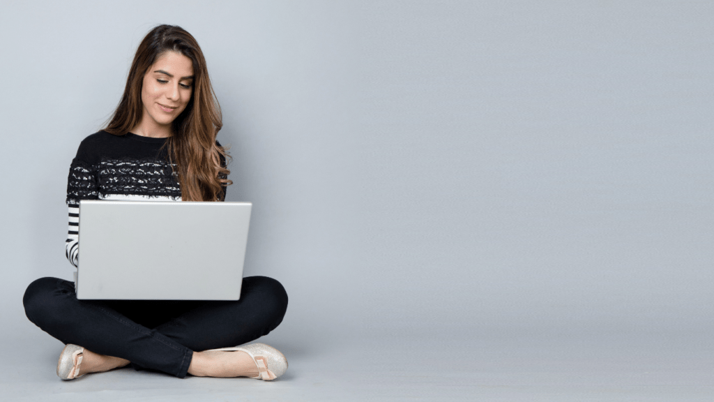 a person is sitting on the floor using a laptop