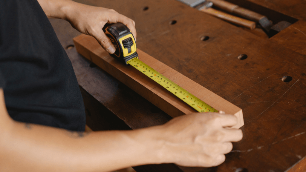 a person is using a ruler to measure a piece of wood