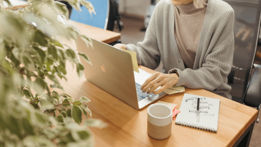 a person sitting at a desk with a laptop and a cup of coffee