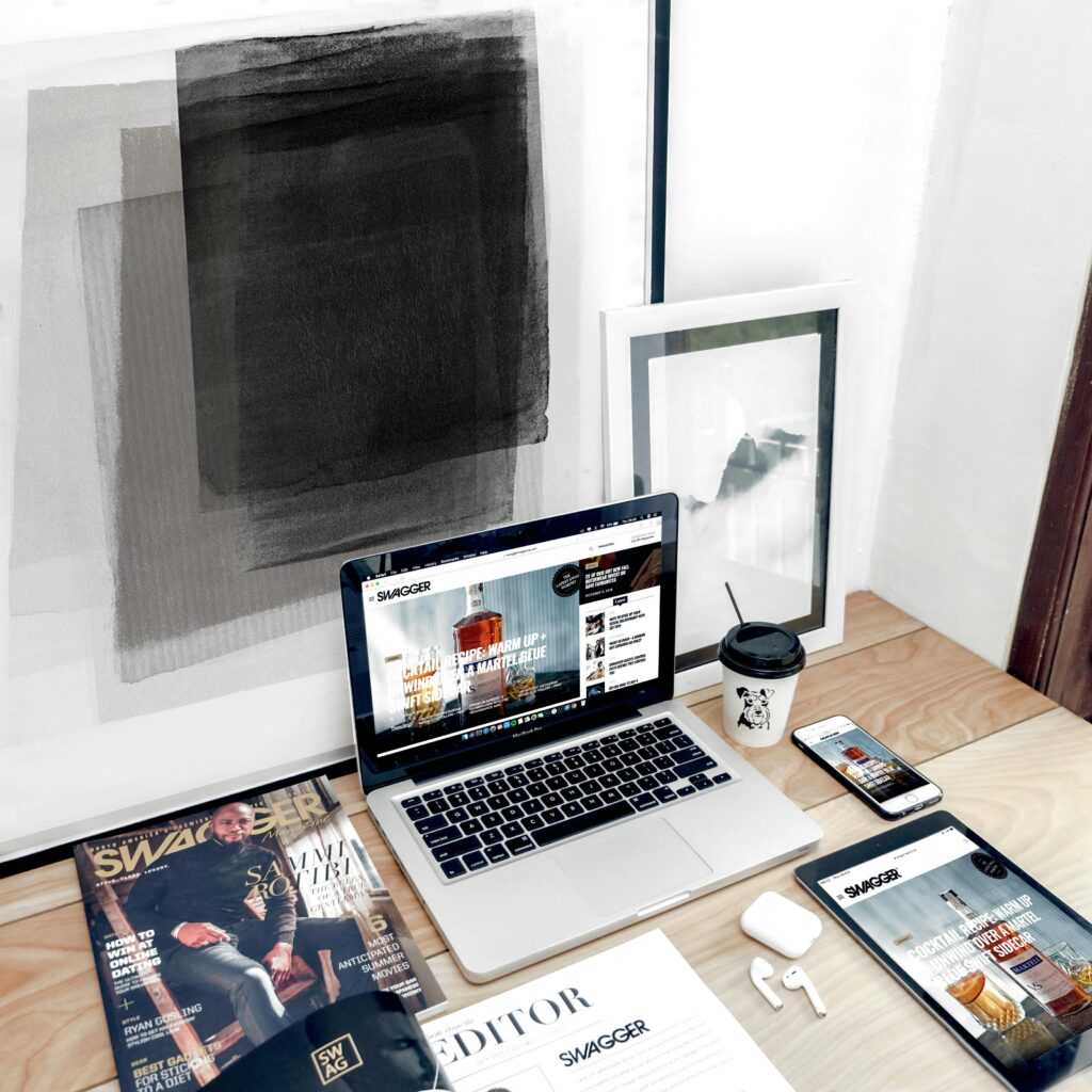 Stylish workspace with a laptop, smartphone, and magazine on a desk. Ideal for digital nomads.